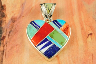 Genuine Turquoise, Spiny Oyster Shell and Blue Lapis inlaid between ribbons of Sterling Silver. Beautiful Fire and Ice Lab Opal Accents with Precision inlay on the bale and pendant. Free 18" Sterling Silver Chain with Purchase of Pendant. Stunning Heart Pendant Designed by Navajo Artist Calvin Begay. Signed.